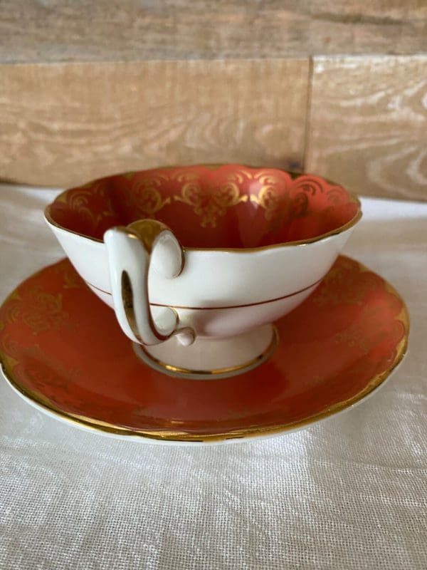 Aynsley bone china tea cup in burnt orange, white, gold trim and floral handle side