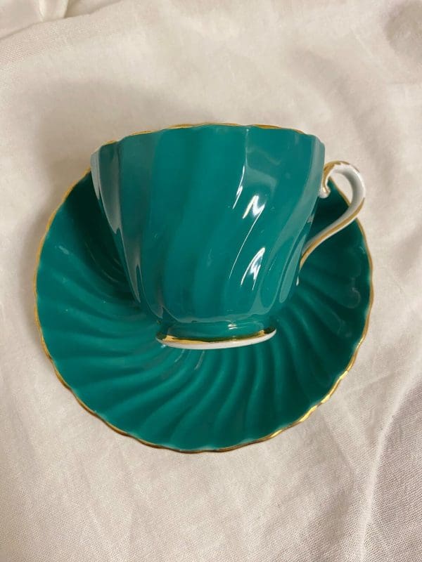 Aynsley tea cup and saucer green and gold 1950s on its side