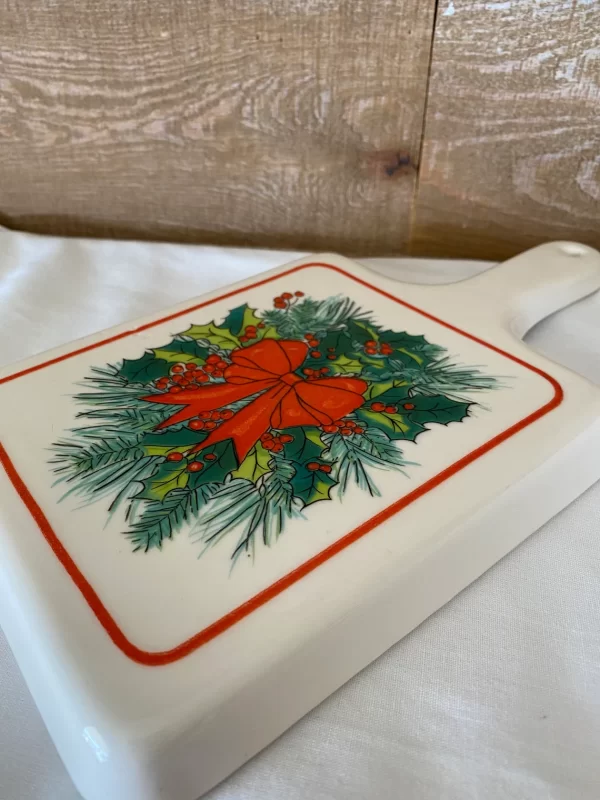 Christmas trivets on flat surface showing the design of a red bow on a holly wreath