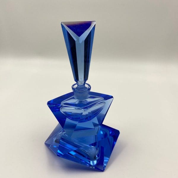 blue crystal perfume bottle on top of trinket dish with trinket dish up side down