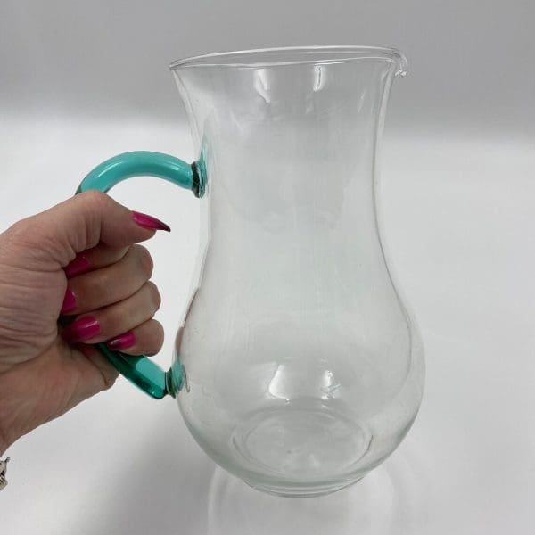 vintage glass water pitcher in hand to show size