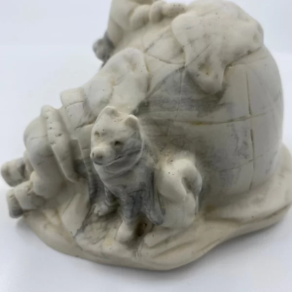 carved soapstone figurines close of dog next to igloo