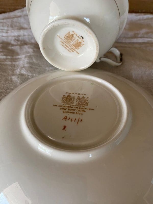 Paragon fine bone china tea cup and saucer with colorful flowers on blue backdrop showing bottom of both with Paragon double warrant