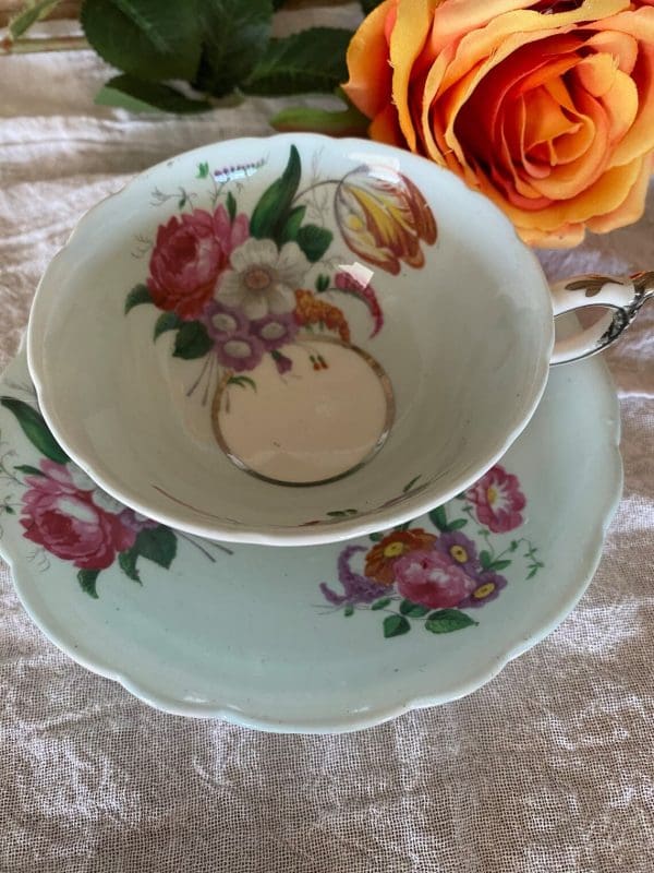 Paragon fine bone china tea cup and saucer with colorful flowers on blue backdrop top view