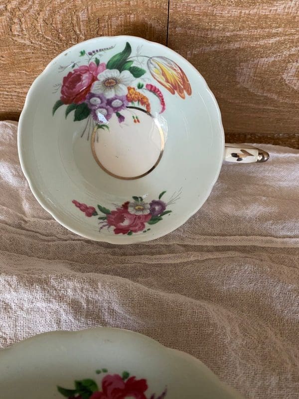 Paragon fine bone china tea cup and saucer with colorful flowers on blue backdrop against a woodgrain wall