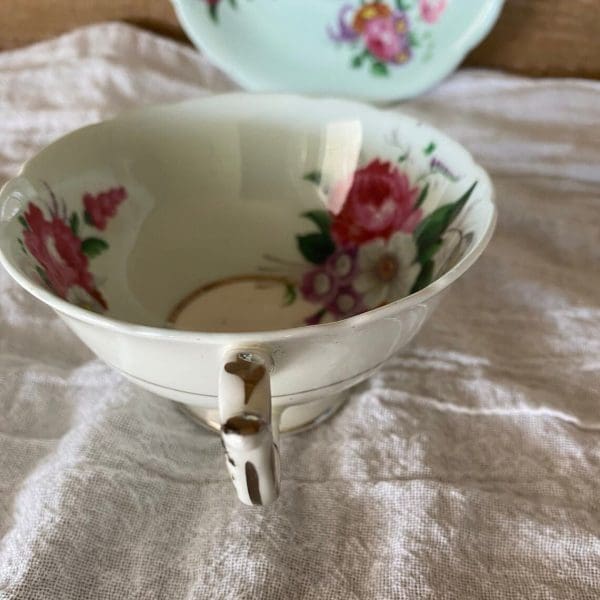 Paragon fine bone china tea cup and saucer with colorful flowers on blue backdrop close u of handle showing slight wear to gold trim