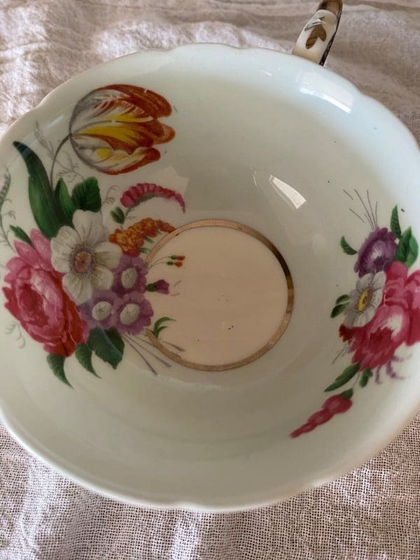 Paragon fine bone china tea cup and saucer with colorful flowers on blue backdrop close up of tea cup