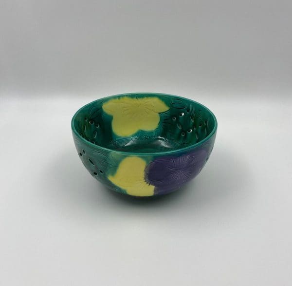 vintage green pottery bowl embossed colorful floral design in yellow and purple