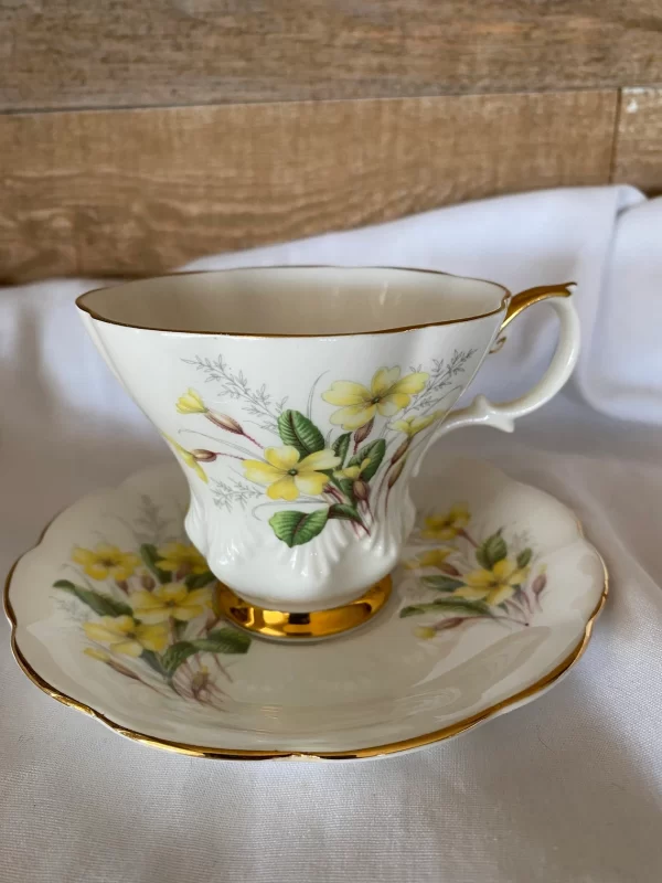 Royal Albert tea cups yellow flowers, green petals on white backdrop and gold trim