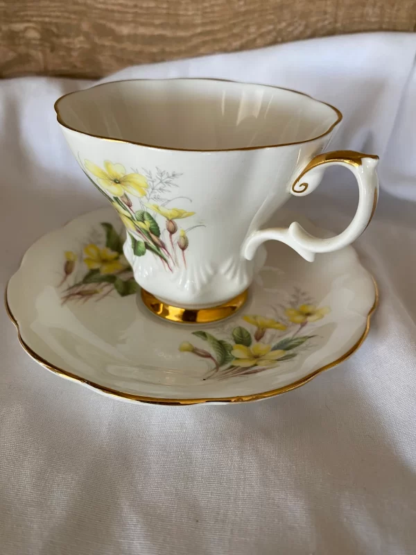 Royal Albert tea cups yellow flowers, green petals on white backdrop and gold trim standard view