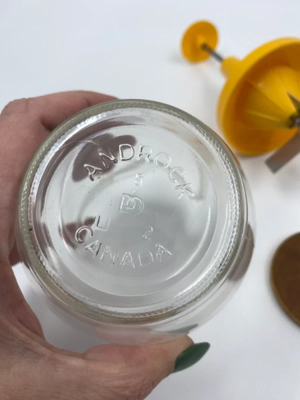 manual nut chopper bottom of jar in hand to show size and embossed Androck Canada