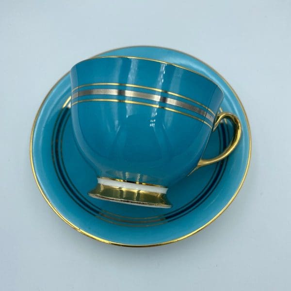 Aynsley England bone china Turquoise Blue Tea Cup and Saucer Set teacup on side on top of saucer showing off the color and gold bands