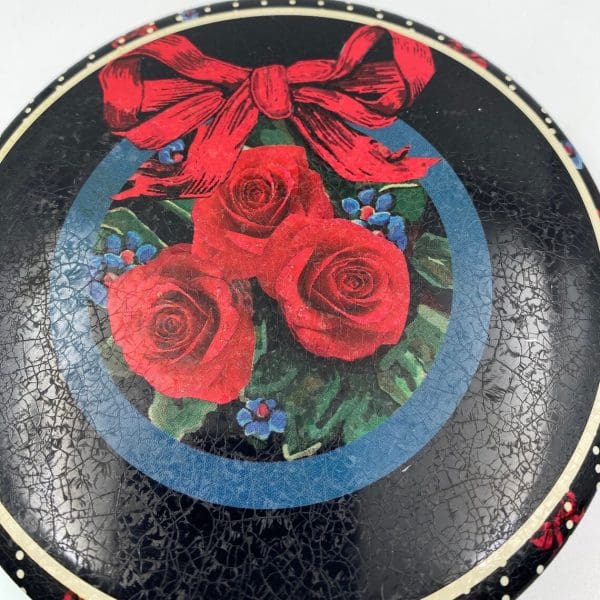 vintage cookie tins top showing red roses and a red bow on black ground