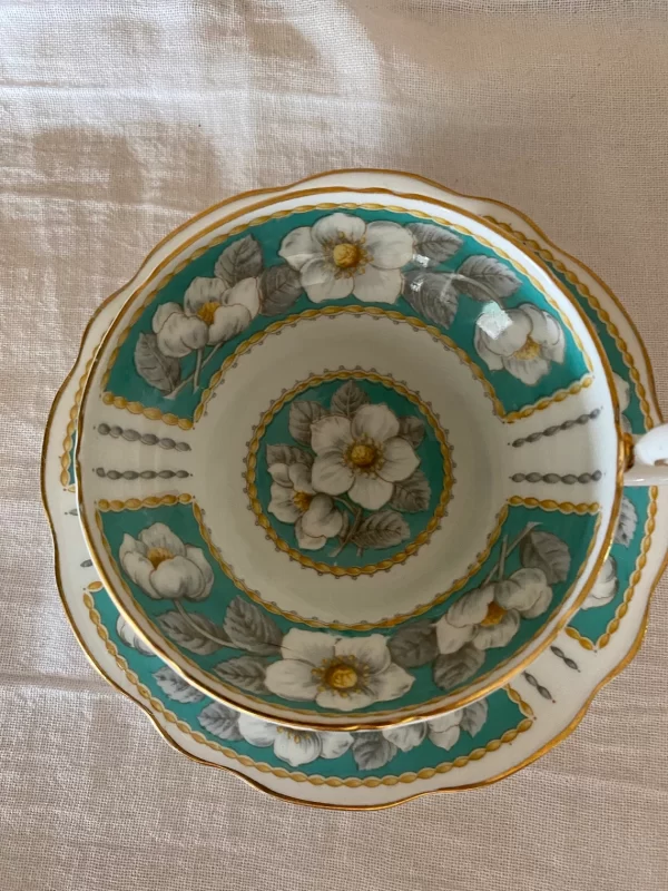 Foley teacup and saucer close to show design of white wild roses on teal green