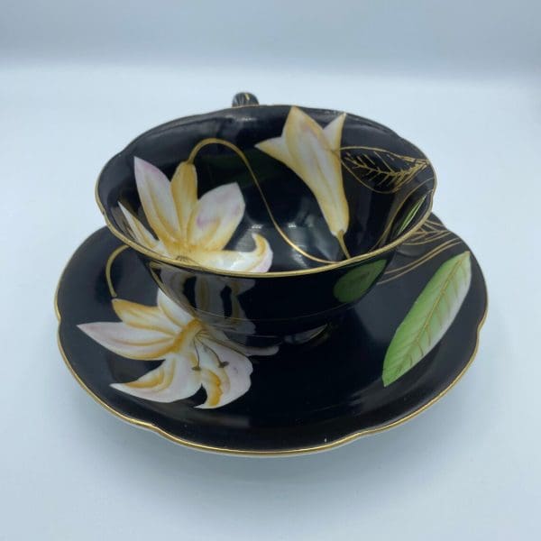 Occupied Japan tea cup and saucer black with lily flower handle in back