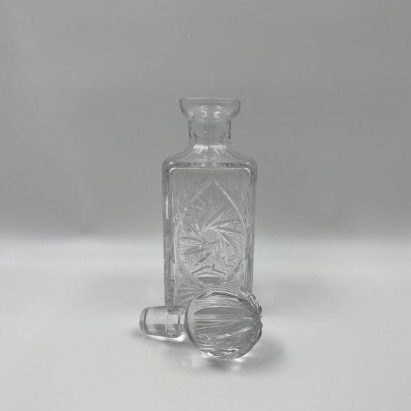 vintage square crystal decanter with stopper laying in front