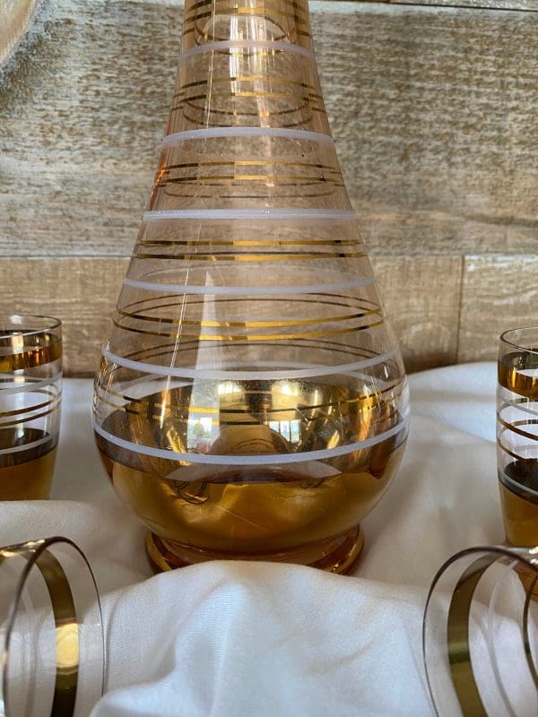 amber glass decanter with stopper gold and white stripes and four matching cups close