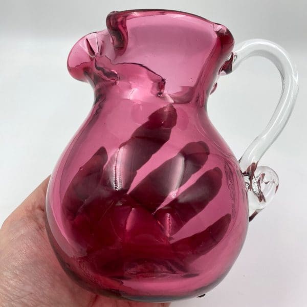 vintage pink glass pitcher in hand to show size